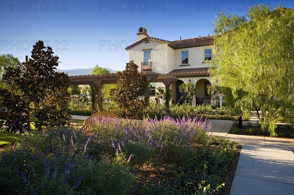 Exterior contemporary Spanish style home with lush gardens