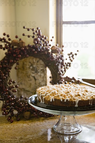 Glass platter holding coffee cake on counter near window