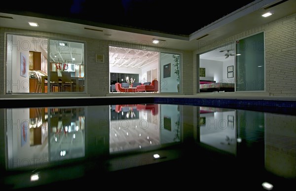 Night view in towards living room of home across pool