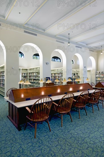 Interior of library with lamps and chairs at study desk in library