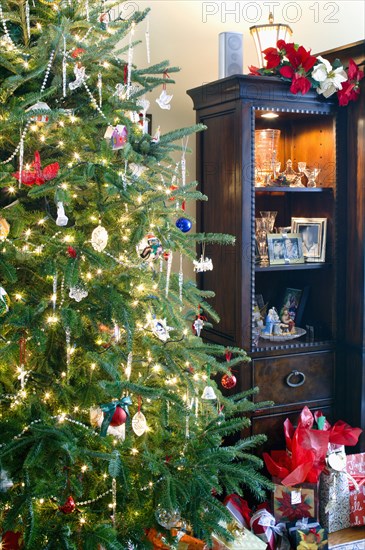 Close-up of decorated lit Christmas tree and gift boxes