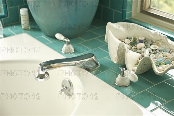 Decorative shells on aqua tile bathroom counter near sink