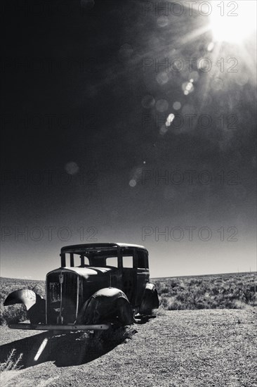 Vintage car missing tires in remote field