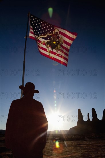 Man holding United States flag with Native American depiction near rock formations