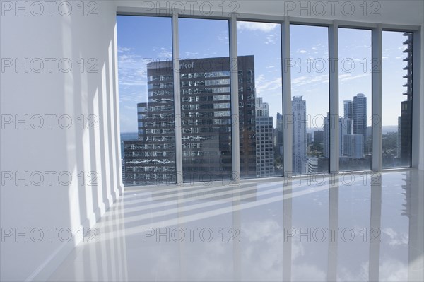 Windows overlooking cityscape in empty modern apartment