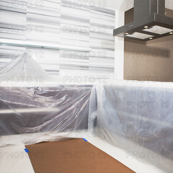 Tarps covering surfaces in modern kitchen under renovation