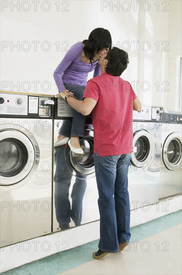 Asian couple kissing in laundromat