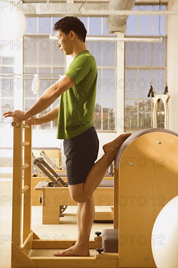 Asian man stretching on exercise equipment