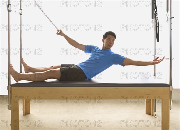 Asian man stretching on exercise equipment