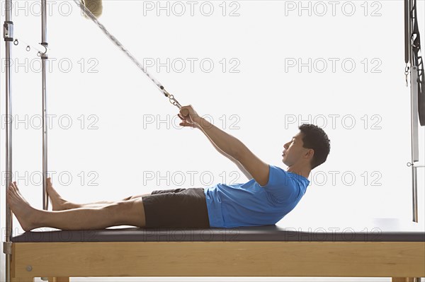 Asian man stretching on exercise equipment