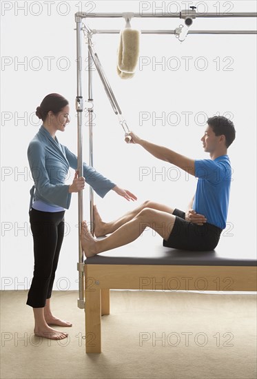 Instructor helping man on exercise equipment