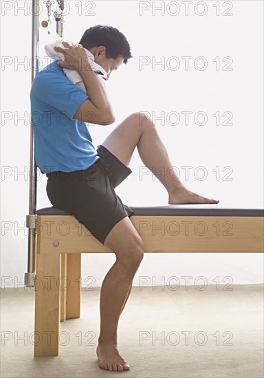 Asian man sitting on exercise equipment