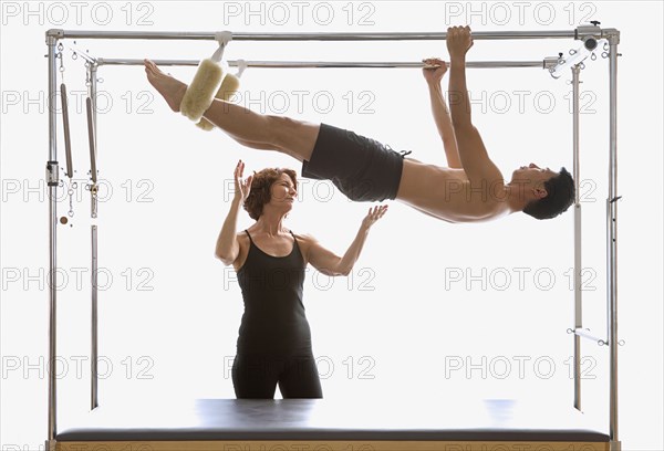 Instructor spotting man on exercise equipment