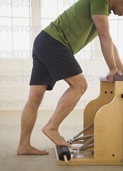 Asian man stretching on exercise equipment