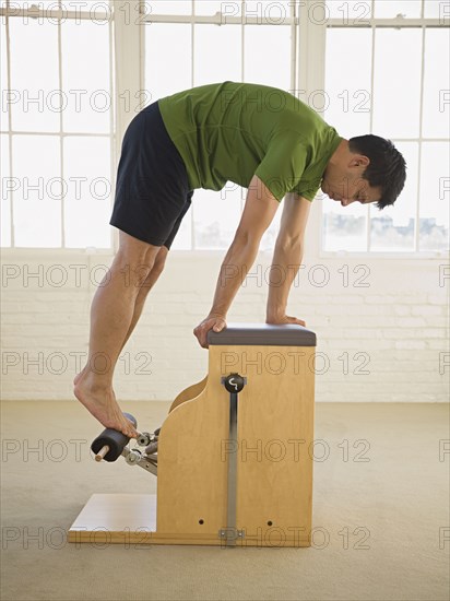 Asian man stretching on exercise equipment