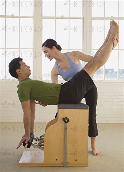 Instructor helping man in exercise studio