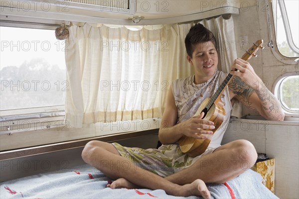 Mixed race man playing ukulele