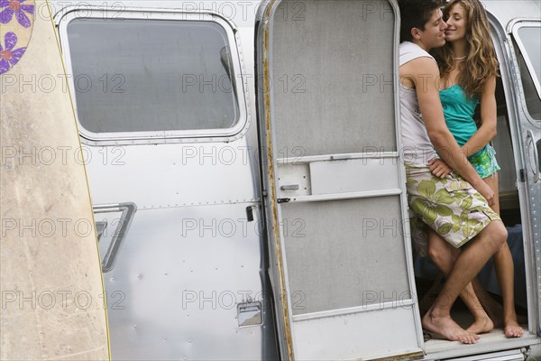 Multi-ethnic couple hugging in doorway of camper