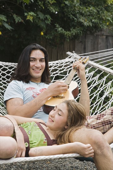 Pacific Islander man playing ukulele for sister