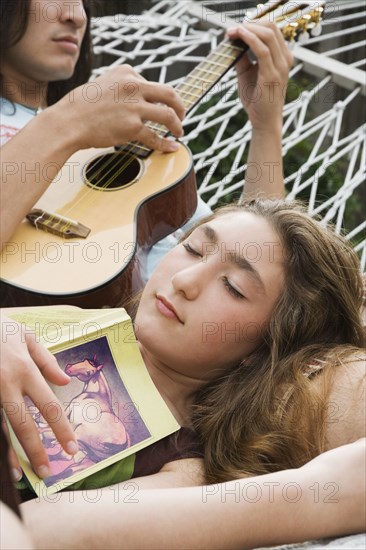 Pacific Islander man playing ukulele for sister