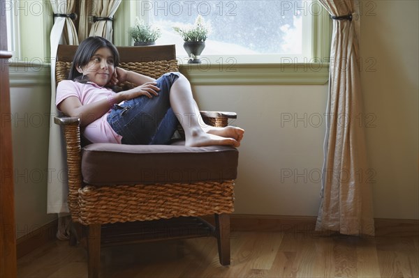 Hispanic girl sitting in armchair