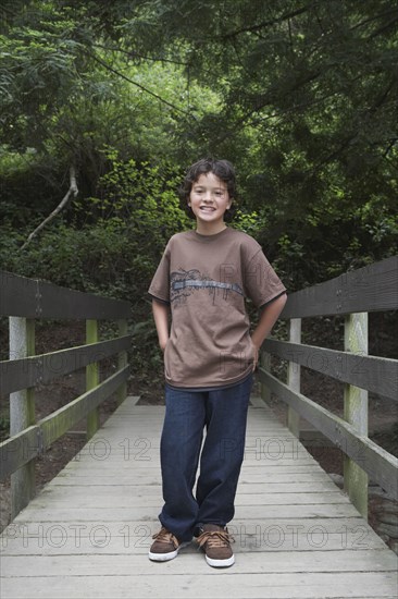 Mixed race boy crossing wooden bridge