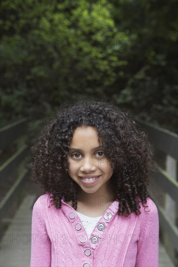 Mixed race girl crossing wooden bridge