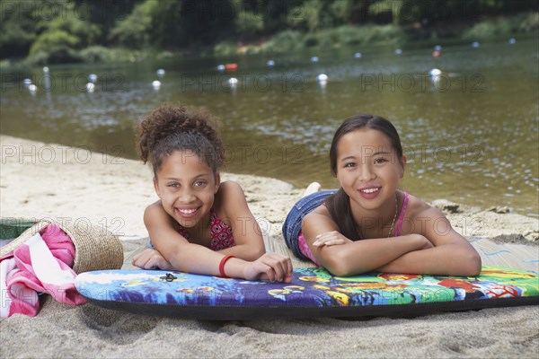 Friends laying on boogie board near lake