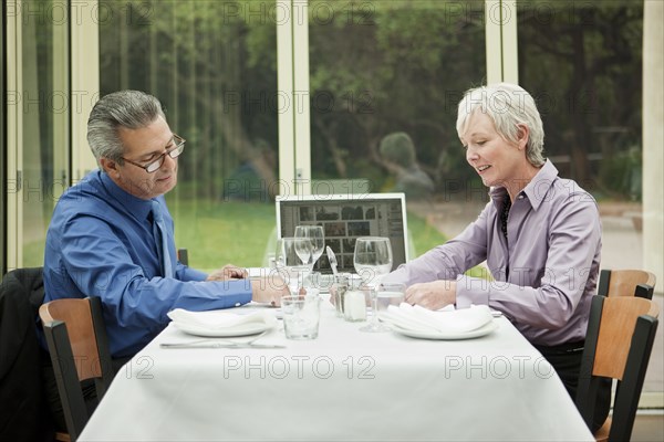 Business people with laptop working at table in restaurant