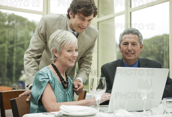 Business people using laptop at table in restaurant