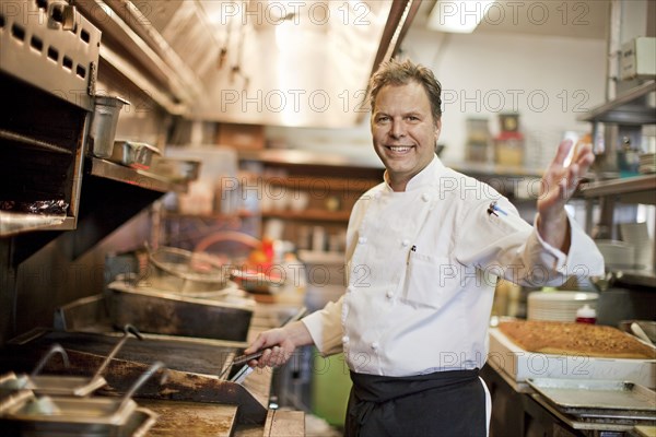 Portrait of Caucasian chef waving in restaurant kitchen