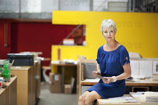 Portrait of serious Caucasian businesswoman sitting on desk