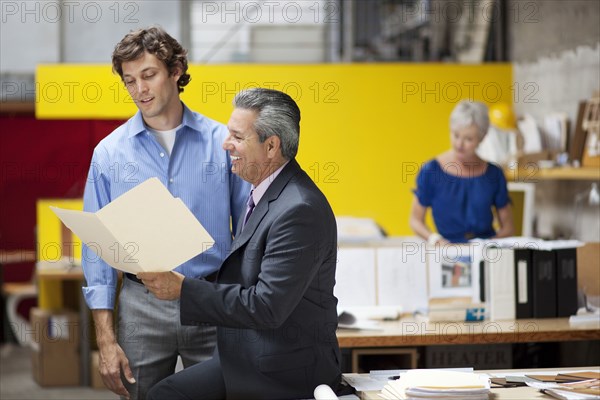 Businessmen reading file folder in office