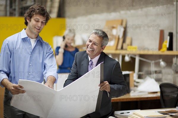 Architects reading blueprints in office