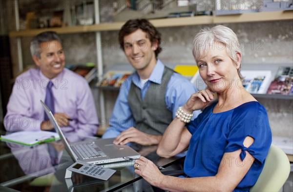 Portrait of smiling businesspeople using laptop in office