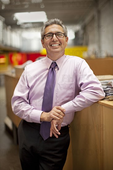 Portrait of smiling Hispanic businessman leaning on desk