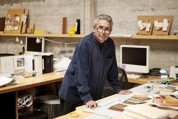 Portrait of serious Hispanic designer examining color swatches in office