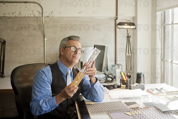 Hispanic businessman in office examining part