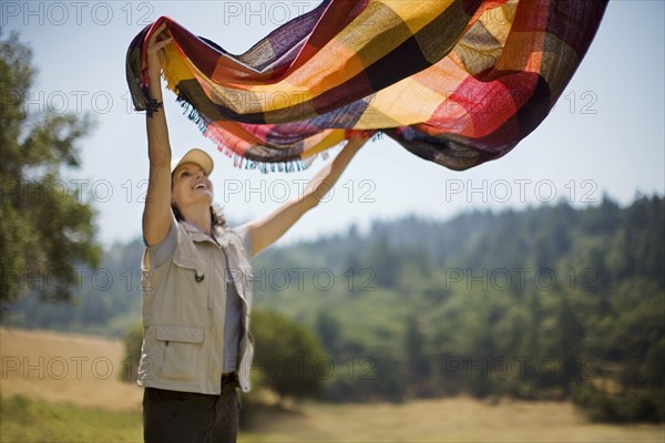 Hispanic woman spreading picnic blanket outdoors