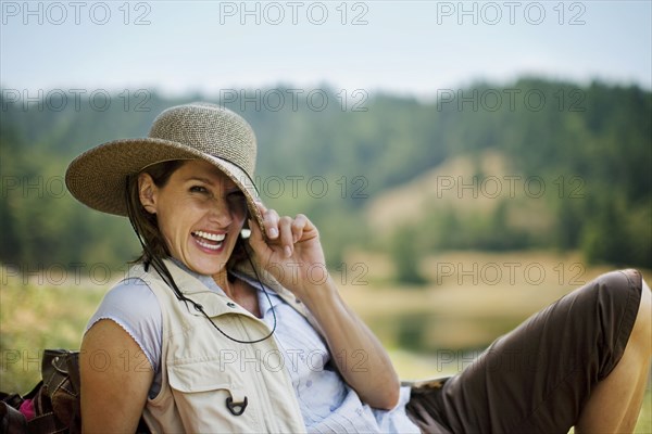 Portrait of playful Hispanic woman pulling brim of hat