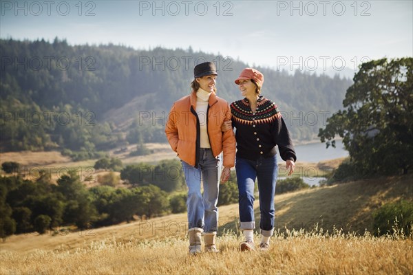 Women walking arm in arm near field