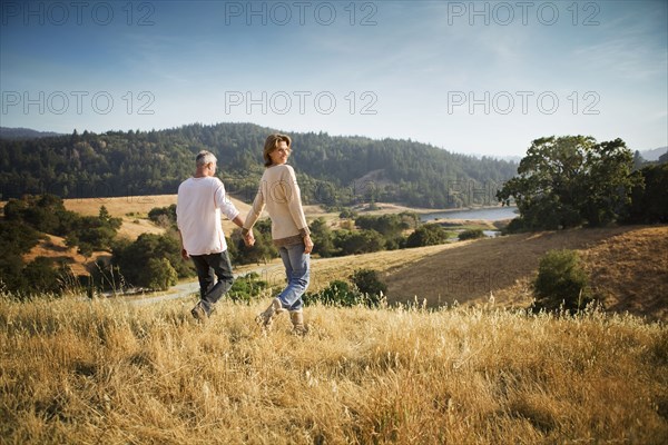 Couple holding hands walking in field