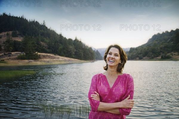 Smiling Hispanic man standing near lake