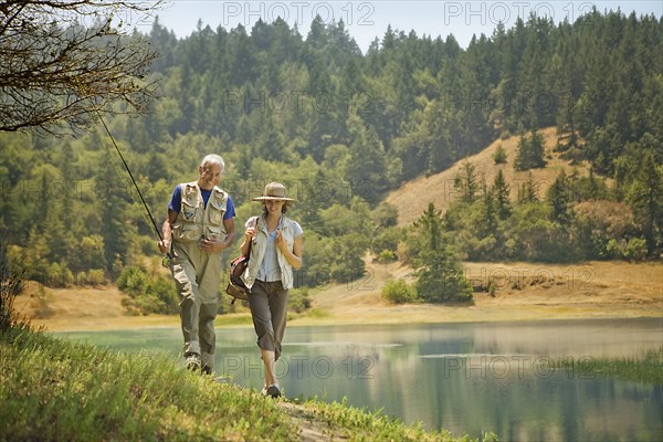 Couple walking with fishing rod near river