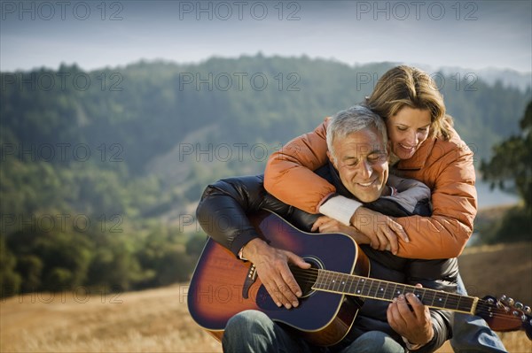 Woman hugging man playing guitar