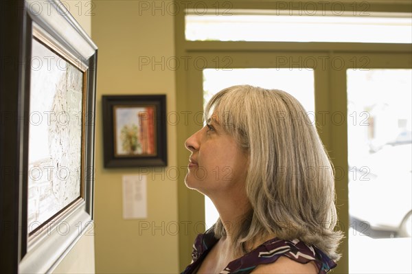 Caucasian woman admiring painting in gallery