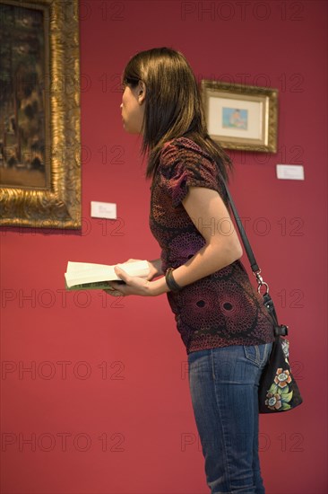 Middle Eastern woman admiring painting in museum