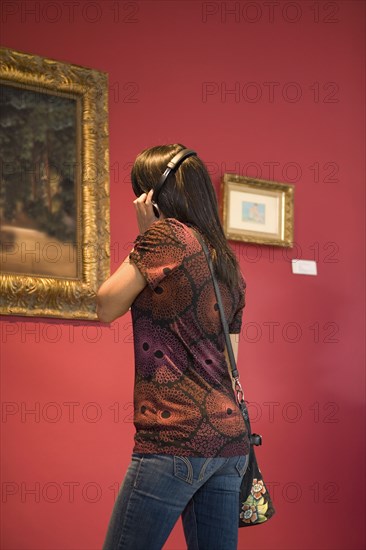 Middle Eastern woman admiring painting in museum