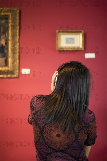 Middle Eastern woman admiring painting in museum