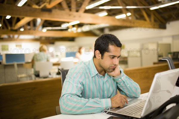 Pacific Islander businessman using laptop in communal workspace